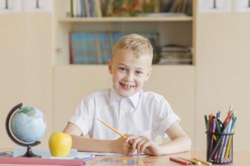 cheerful-boy-sitting-school-desk-2